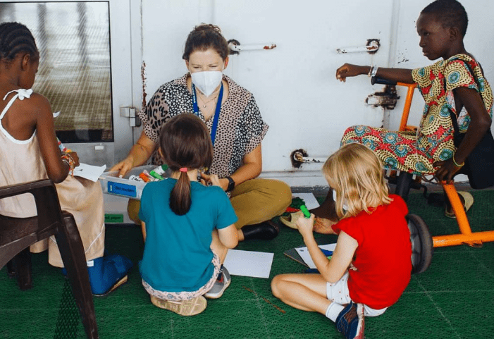 Carey-Anne Dooley, Evie's teacher and her fellow classmate playing with patients on Deck 7 on board a hospital ship. © Mercy Ships