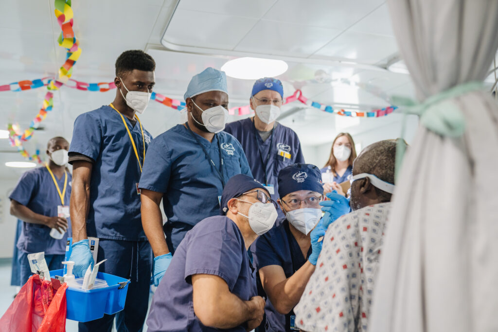 Payam Farzad, Max Fax Surgeon, Leo Cheng, Max Fax Surgeon, Gracious Sankulani, Education Training and Advocacy Resident, and Gary Parker, Emeritus Chief Medical Officer, with a patient.