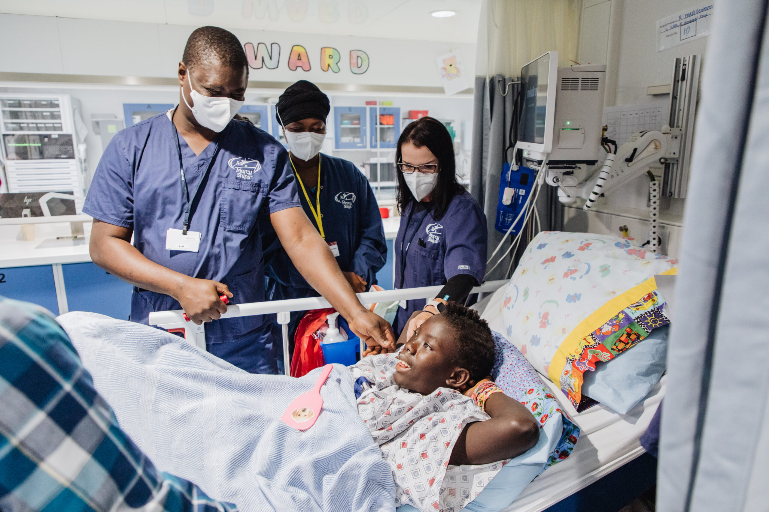 Dr. Abraham Camara, Abraham Camara, Plastics Surgeon mentee, visits Lucy, maxillofacial patient, during Ward Rounds.