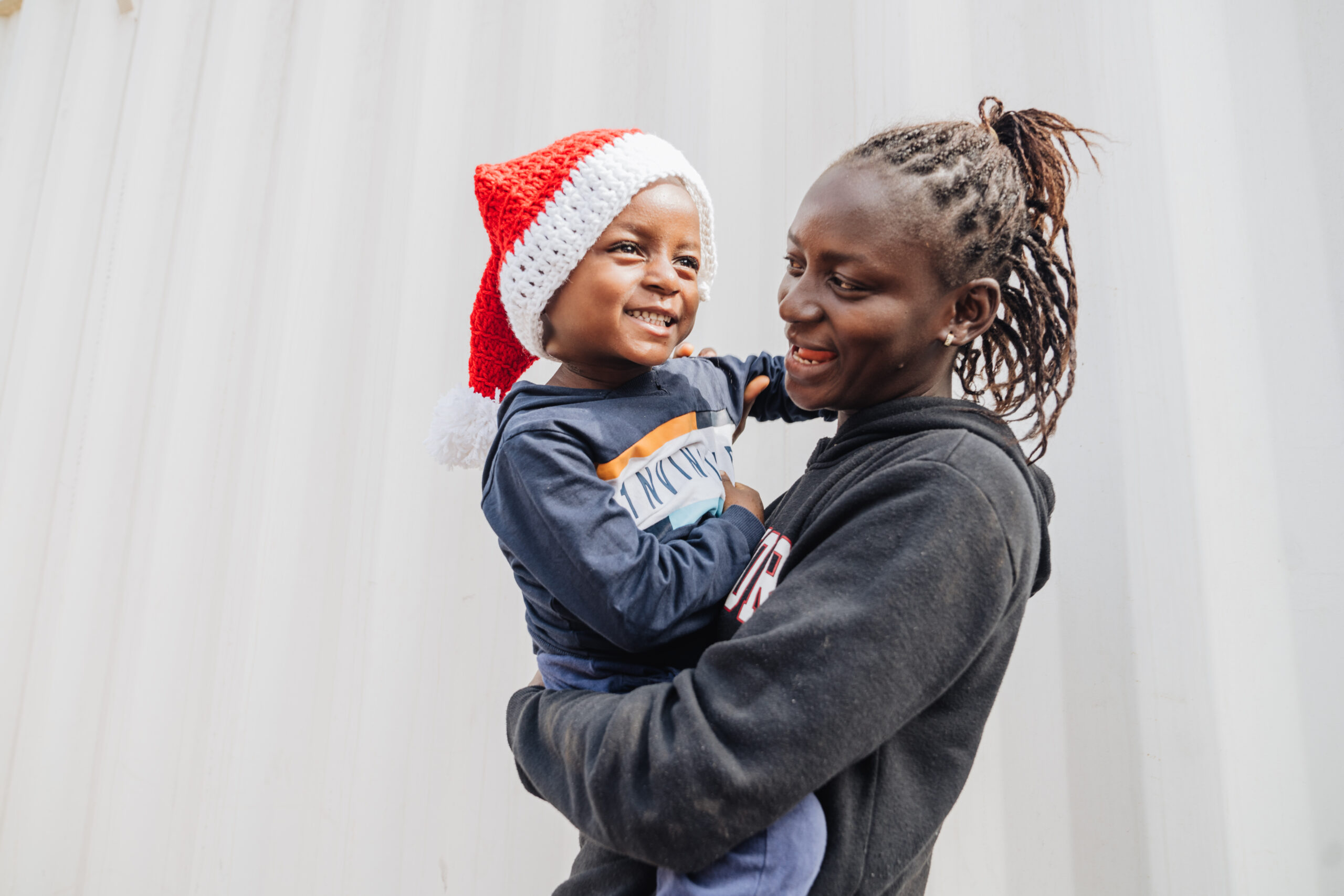 Emmanuel, maxillofacial patient, with his mother wearing a christmas hat.